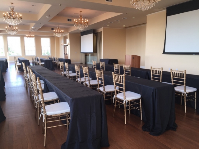 Long classroom tables with black linens face a projection screen at the front of the room.