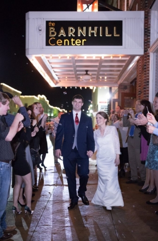 A happily married couple depart their wedding reception at The Barnhill Center as guests line the sidewalk outside and wish them well.